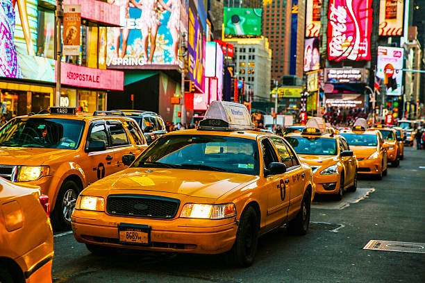Yellow taxis lined up on a busy city street at dusk