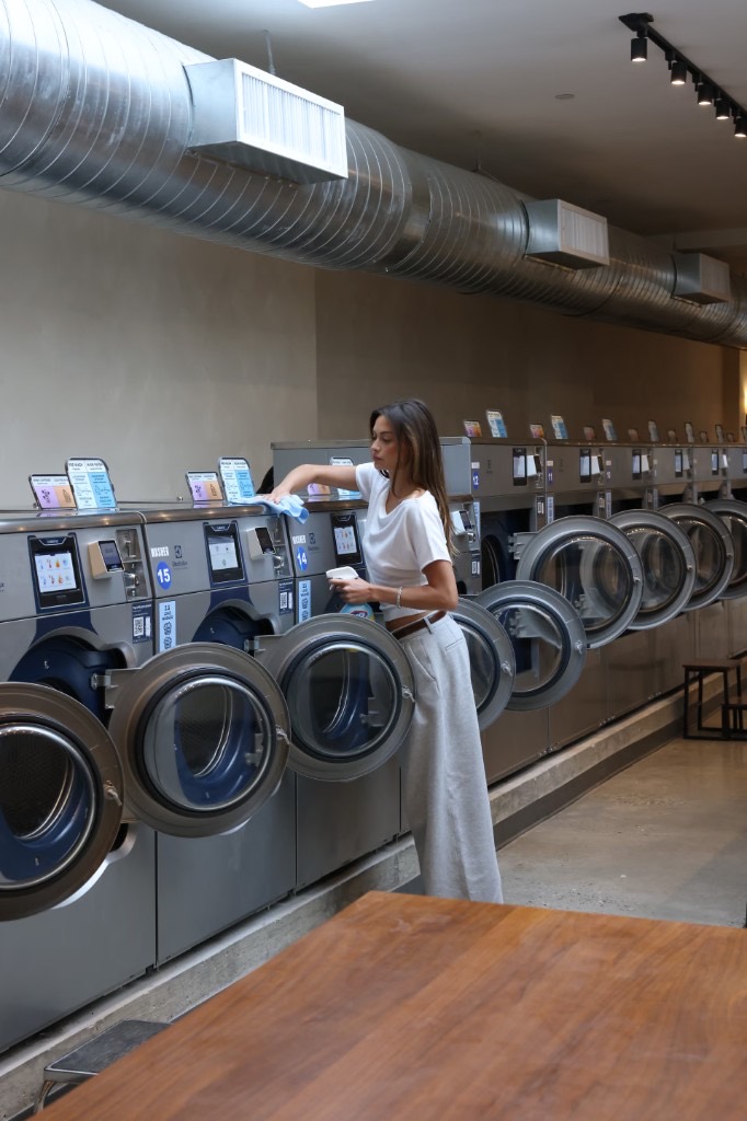 A woman wiping down a row of commercial washers at Launderette
